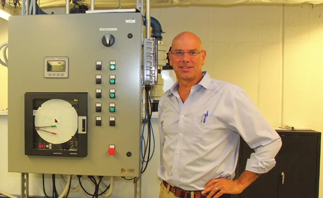 Brian Hagopian beside an industrial wastewater control panel
